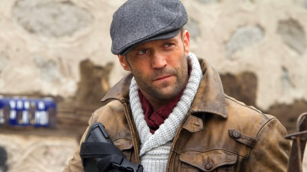 Jason Statham avec une casquette et une arme