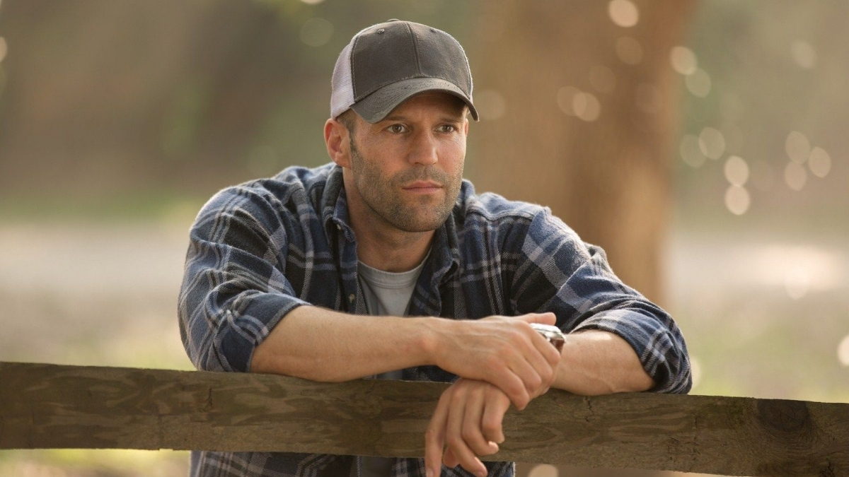 Jason Statham posé sur une barrière en bois