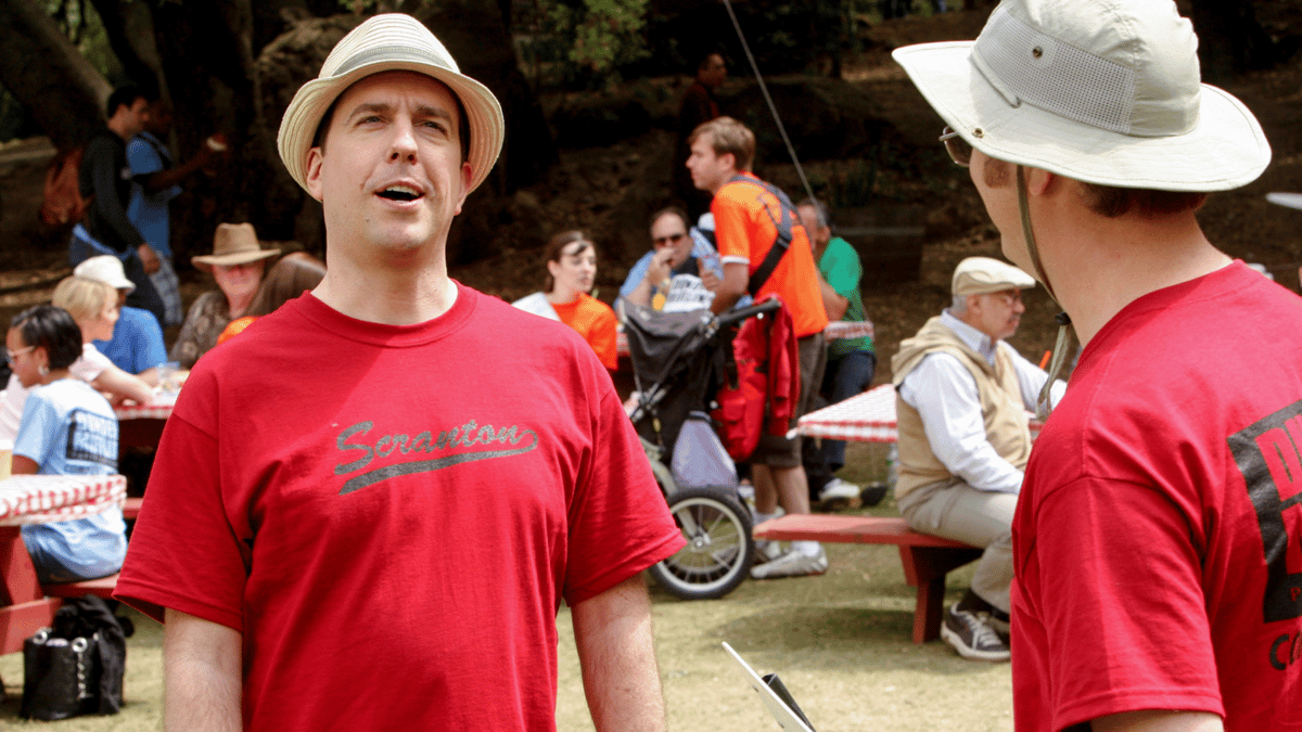 Andy Bernard avec un chapeau et un t-shirt rouge au pique-nique